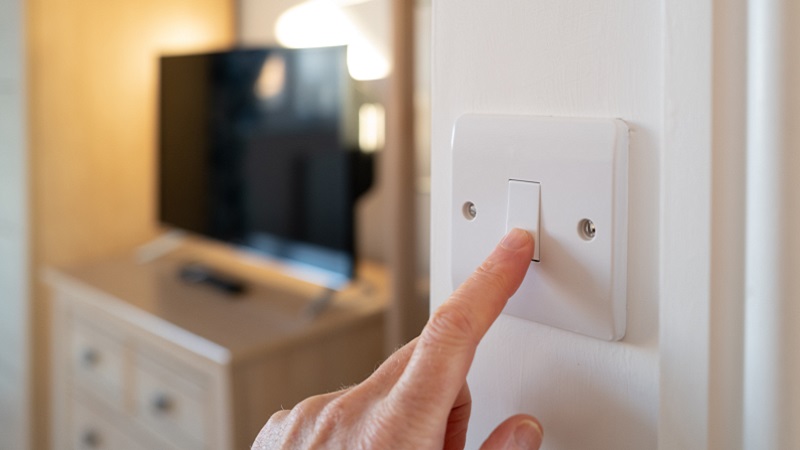 Stock image of a person switching off the lights in a room